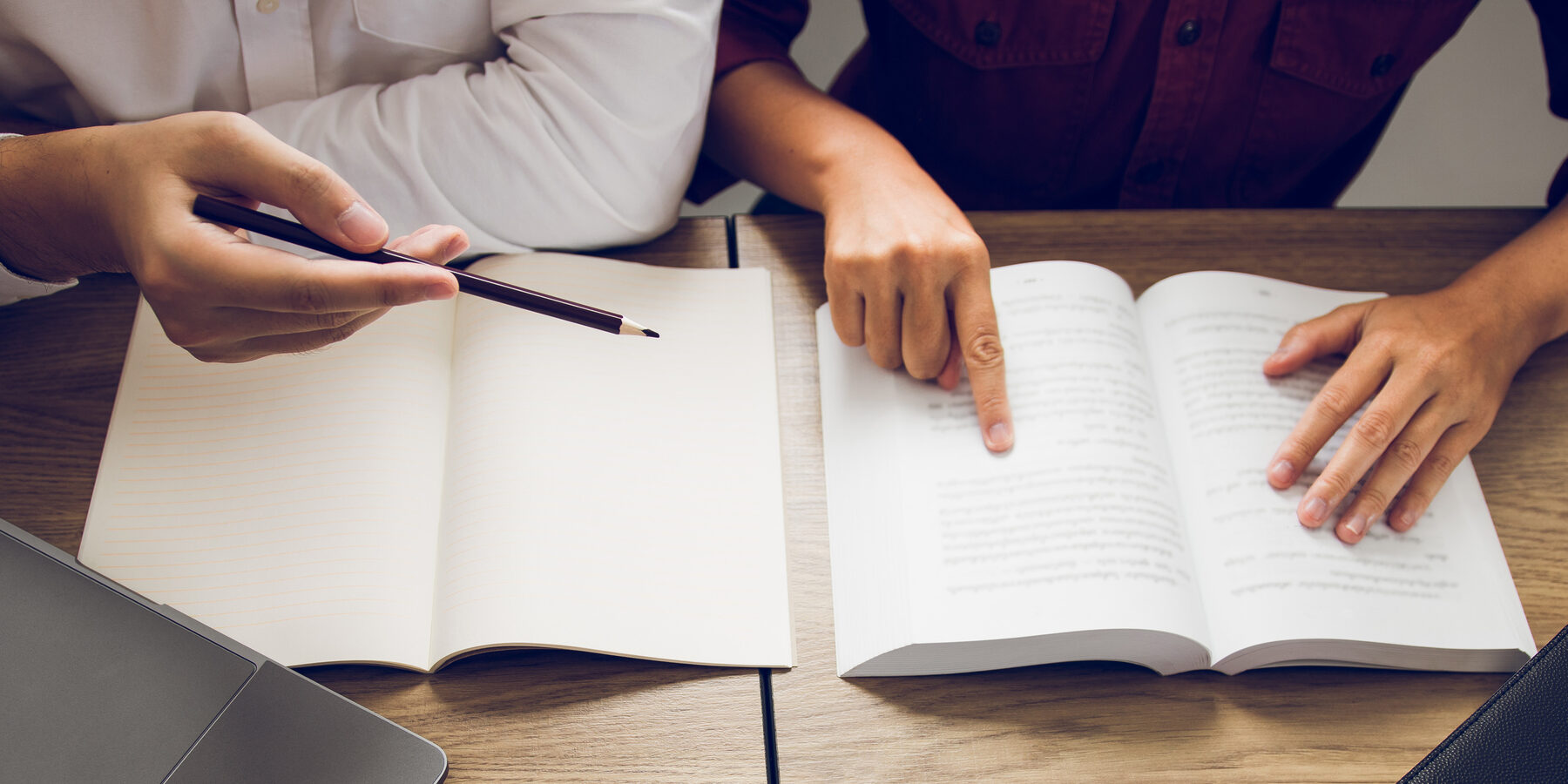 Hands with an open book and pencil at MonteNova Academy